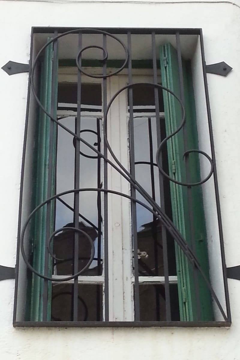 Grille de fenêtre barreaudée ornée de volutes forgées 2