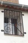 Grille de fenêtre barreaudée ornée de volutes forgées 1